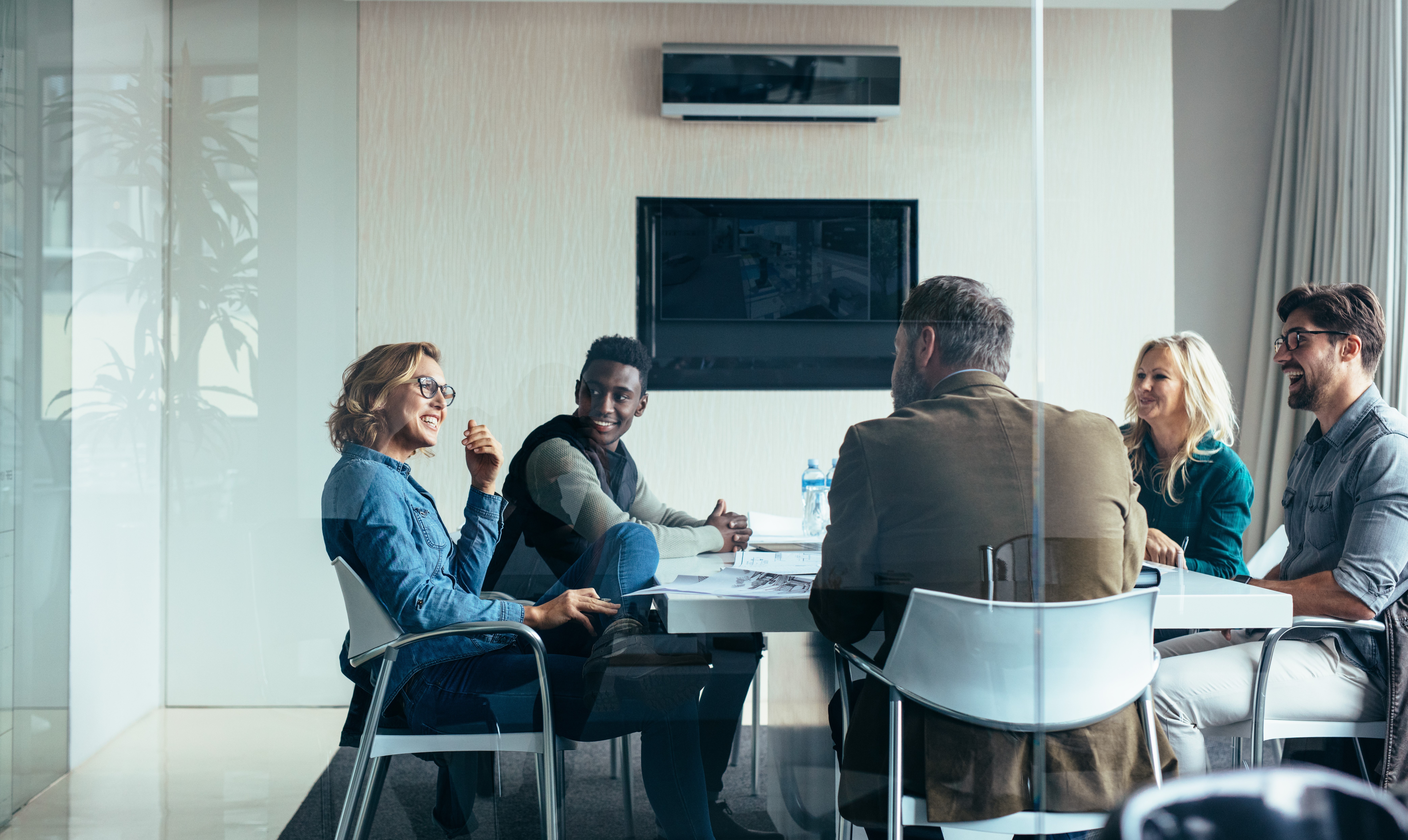 Kollegat hymyilevät kokoushuoneessa