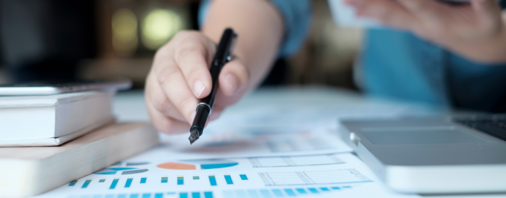 Henkilöllä on kynä kädessä ja hän tutkii raporttia