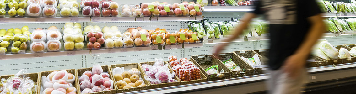 Henkilö kävelee kaupan hedelmä- ja vihannesosastolla