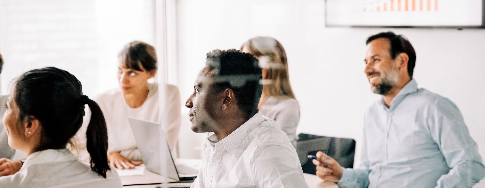 Kollegat hymyilevät lasisessa kokoushuoneessa modernissa toimistossa