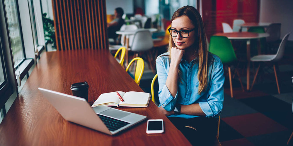 Nainen katsomassa tietokoneruutua ja osallistumassa e-Learning-koulutukseen