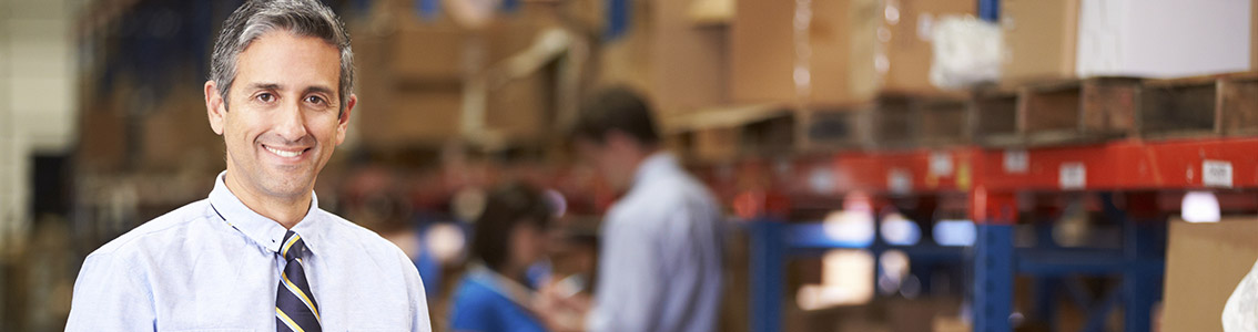 Hymyilevä mies kauluspaidassa ja kravatissa