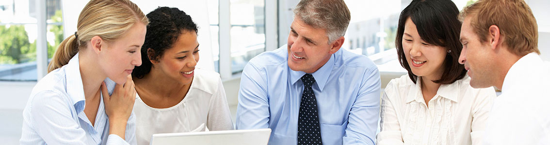 Kollegat istuvat pöydän äärellä modernissa toimistossa ja hymyilevät