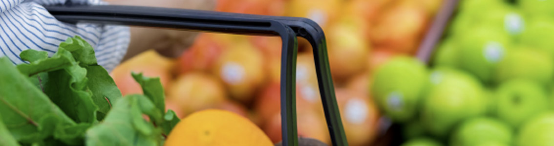 Woman with a shopping basket looking at fruit and vegetables