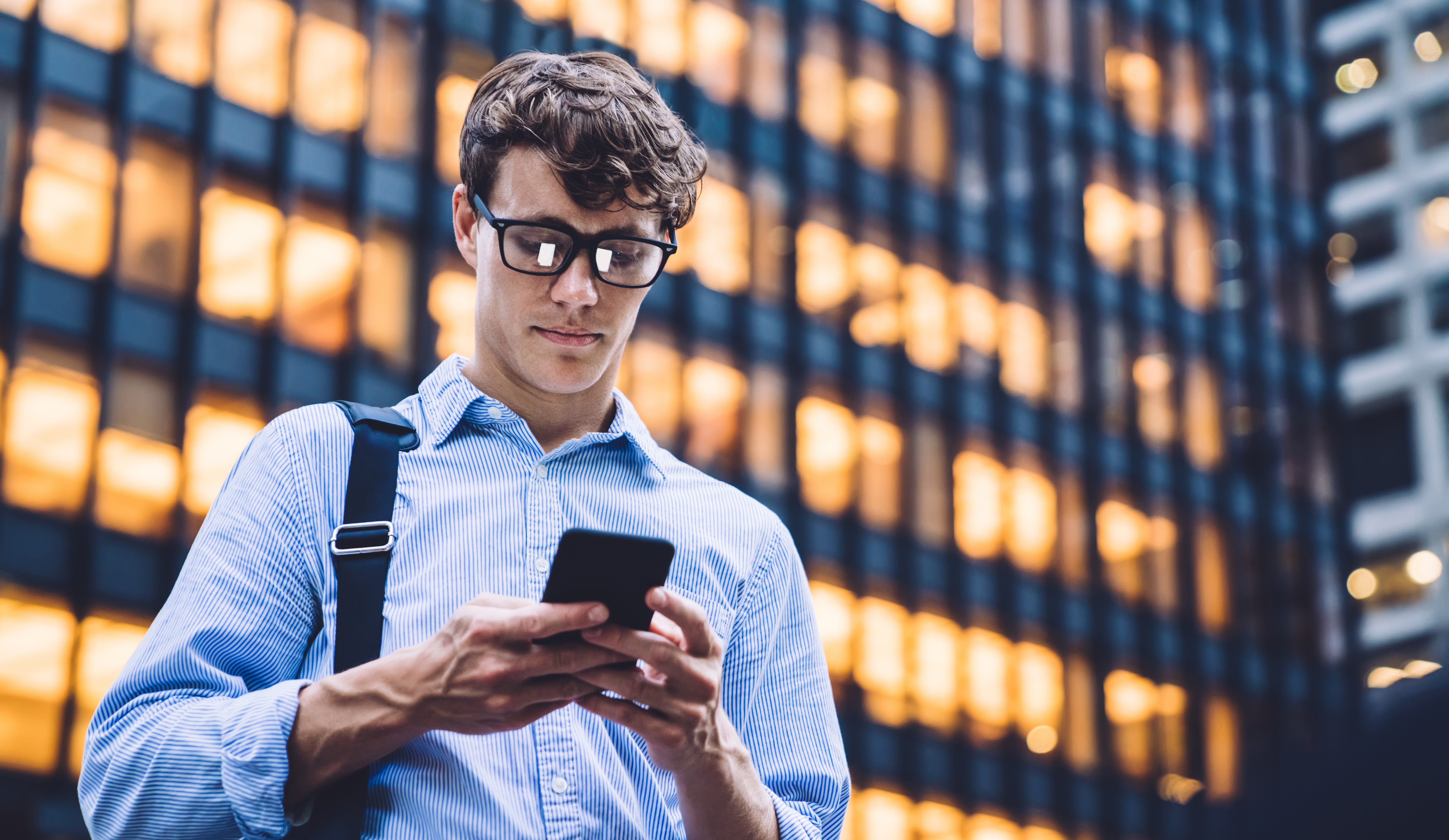 Mies puhelimella kaupunki toimistotalo edessä