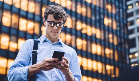 Mies puhelimella kaupunki toimistotalo edessä